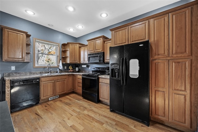 kitchen featuring sink, black appliances, and light hardwood / wood-style flooring