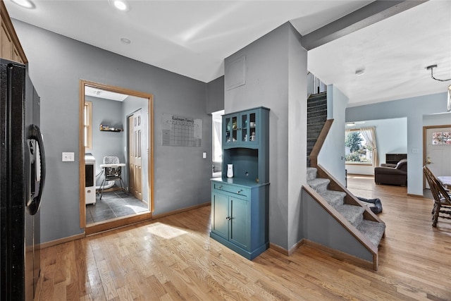 kitchen featuring light hardwood / wood-style floors, black refrigerator with ice dispenser, and blue cabinets