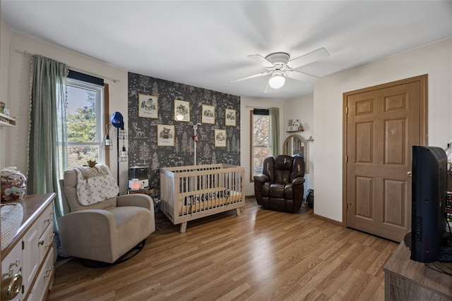 interior space with ceiling fan, light hardwood / wood-style floors, and a nursery area