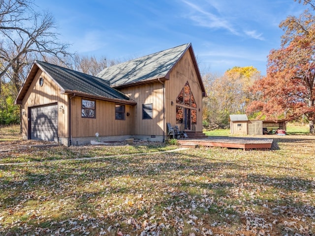 view of property exterior featuring a garage, a wooden deck, a yard, and an outbuilding