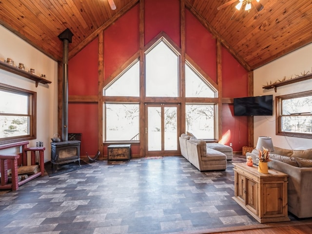 interior space with ceiling fan, high vaulted ceiling, a wood stove, and wooden ceiling