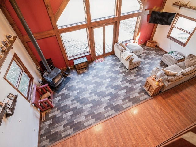 unfurnished living room featuring a wood stove, a high ceiling, and dark hardwood / wood-style flooring