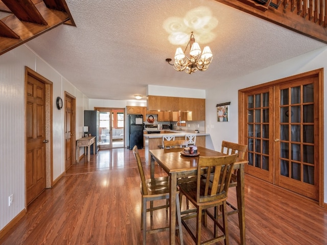 dining room with sink, a textured ceiling, hardwood / wood-style flooring, and an inviting chandelier