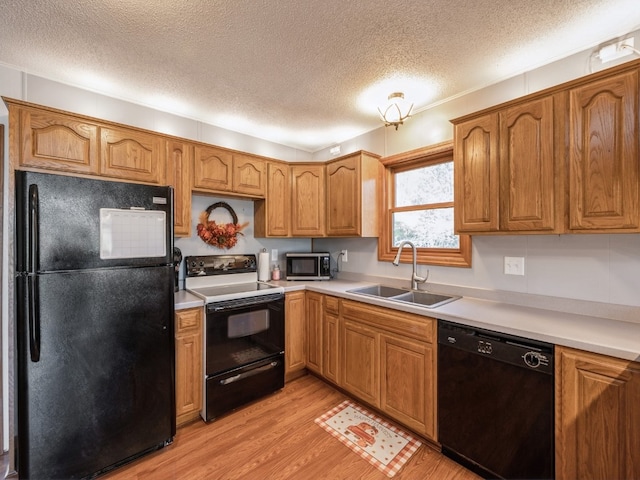 kitchen featuring sink, black appliances, a textured ceiling, and light hardwood / wood-style floors