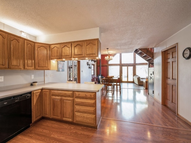 kitchen featuring black dishwasher, kitchen peninsula, a textured ceiling, and dark hardwood / wood-style flooring