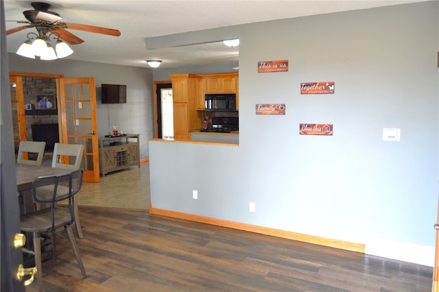 dining area with ceiling fan, a fireplace, and dark hardwood / wood-style floors