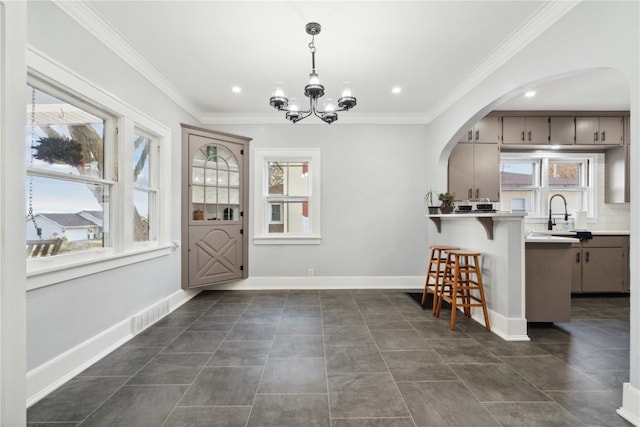 interior space featuring sink, a chandelier, hanging light fixtures, ornamental molding, and kitchen peninsula