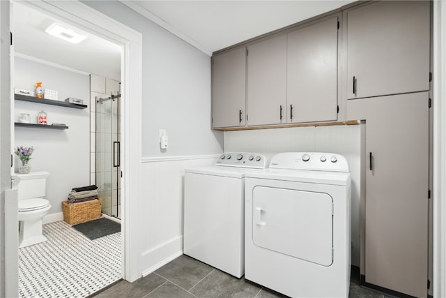 laundry room featuring cabinets, washing machine and dryer, dark tile patterned floors, and crown molding