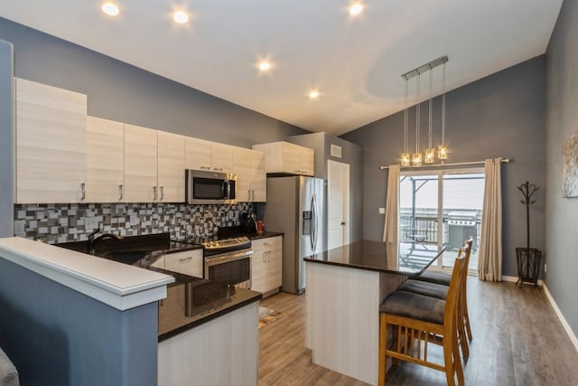 kitchen featuring hanging light fixtures, a breakfast bar, a center island, appliances with stainless steel finishes, and light hardwood / wood-style floors