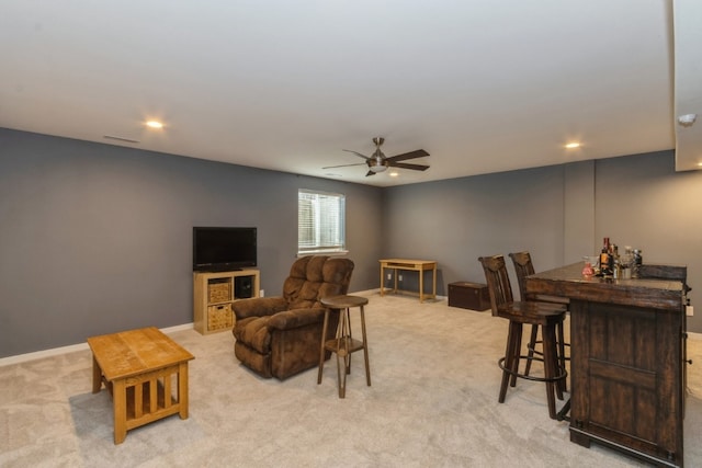 living room with bar area, light colored carpet, and ceiling fan