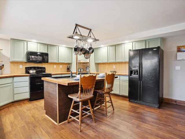 kitchen with green cabinets, wood counters, sink, black appliances, and light hardwood / wood-style floors