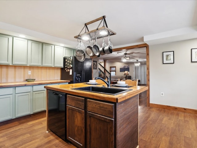 kitchen with black appliances, sink, light wood-type flooring, and a kitchen island with sink