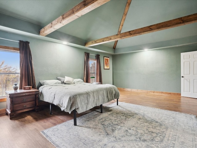 bedroom with hardwood / wood-style flooring and beamed ceiling