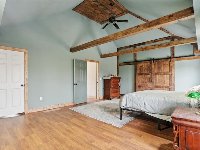 bedroom featuring hardwood / wood-style floors, a barn door, high vaulted ceiling, and ceiling fan