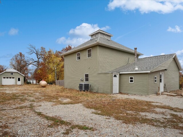 rear view of property featuring an outdoor structure, a garage, and cooling unit