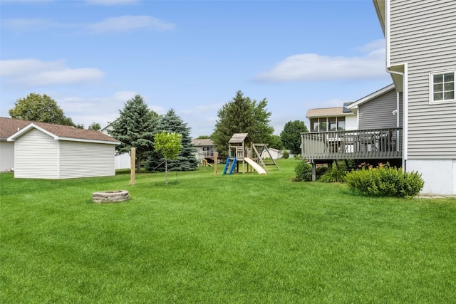 view of yard featuring a deck, a storage unit, and a playground