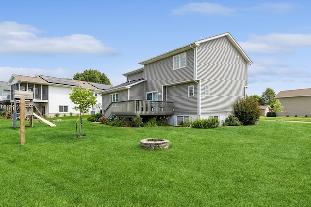 back of house with a lawn, an outdoor fire pit, and a wooden deck