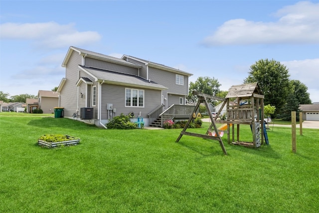 rear view of property with central AC unit, a garage, and a yard