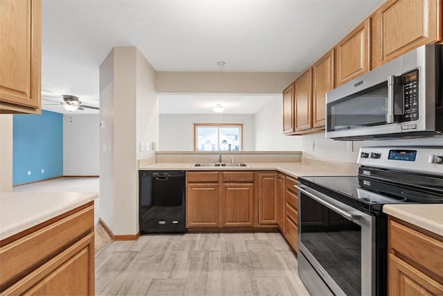 kitchen featuring light wood-type flooring, appliances with stainless steel finishes, sink, and ceiling fan