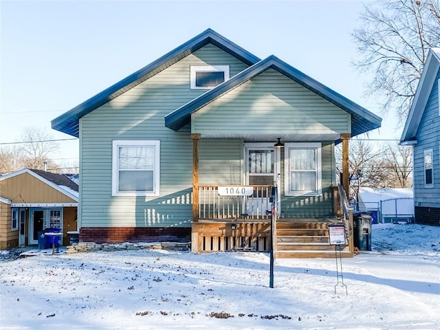 snow covered rear of property featuring a porch