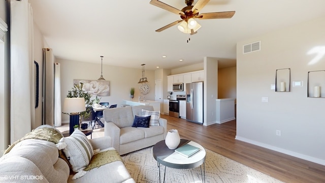 living room featuring sink, wood-type flooring, and ceiling fan