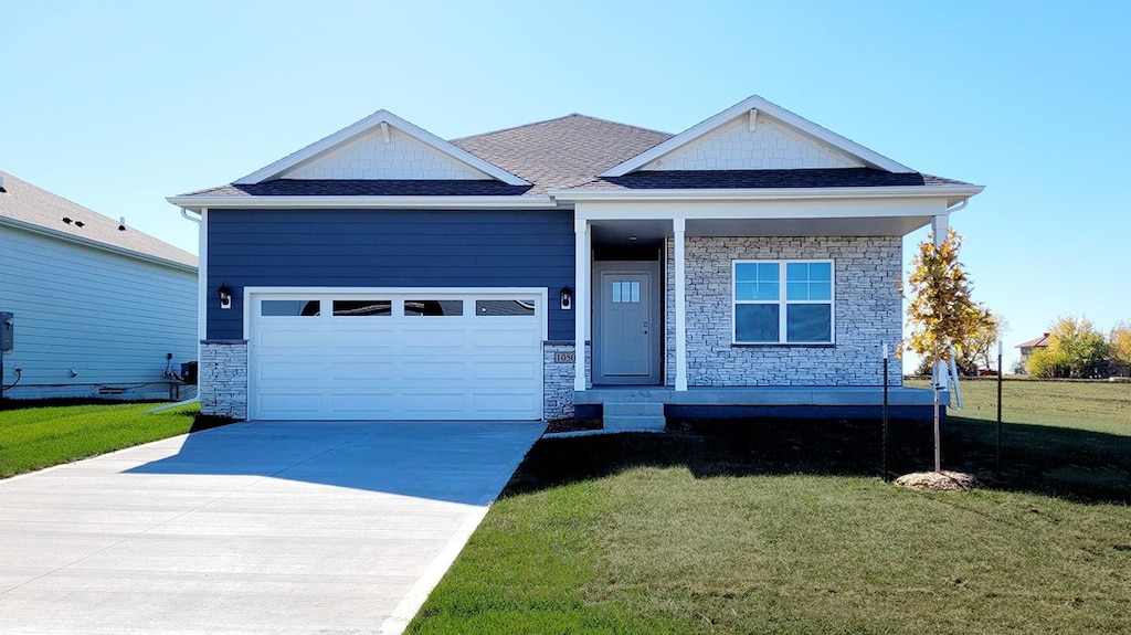 view of front of home featuring stone siding, a garage, driveway, a front yard, and covered porch