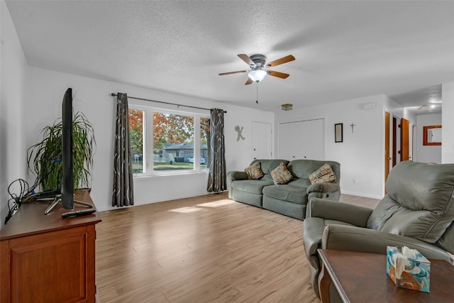 living room featuring light hardwood / wood-style floors, a textured ceiling, and ceiling fan