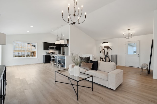 living room featuring lofted ceiling, a notable chandelier, a healthy amount of sunlight, and light hardwood / wood-style flooring