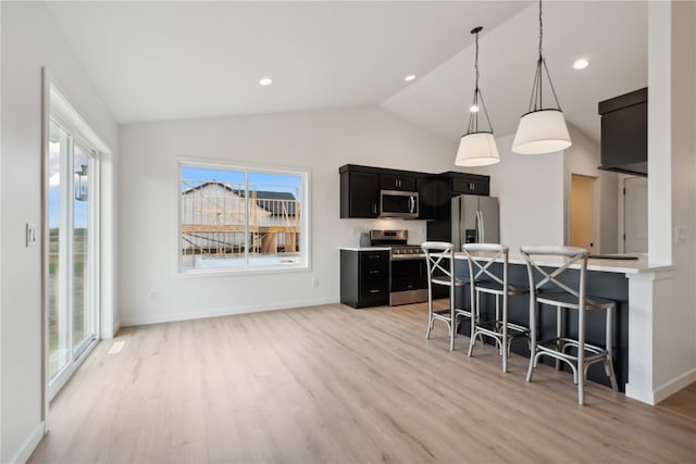 kitchen with appliances with stainless steel finishes, a healthy amount of sunlight, vaulted ceiling, and a kitchen breakfast bar