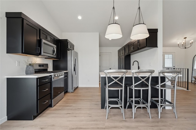 kitchen with stainless steel appliances, light wood-type flooring, hanging light fixtures, an inviting chandelier, and a breakfast bar area