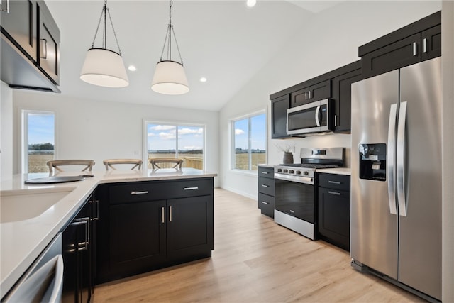 kitchen featuring pendant lighting, vaulted ceiling, light hardwood / wood-style floors, and stainless steel appliances