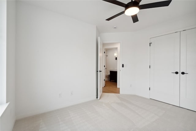 unfurnished bedroom featuring light carpet, ceiling fan, and a closet