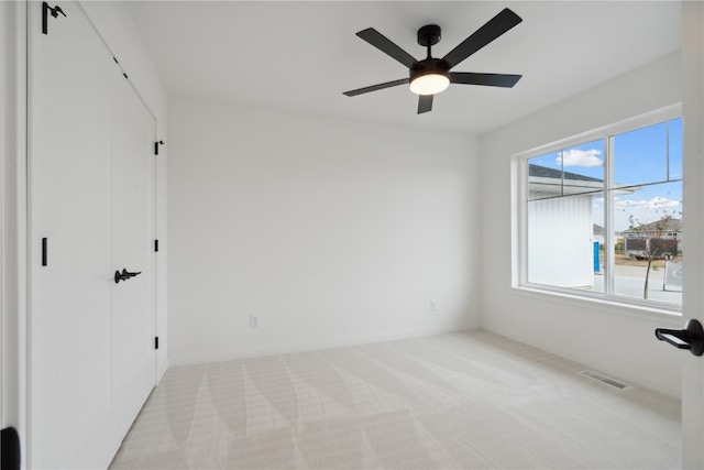 unfurnished bedroom featuring multiple windows, light colored carpet, and ceiling fan