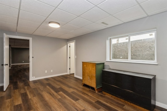 interior space with a paneled ceiling and dark hardwood / wood-style flooring