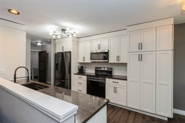 kitchen with white cabinetry, appliances with stainless steel finishes, backsplash, sink, and dark wood-type flooring