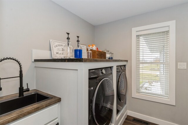 laundry area featuring washing machine and clothes dryer, sink, and dark wood-type flooring