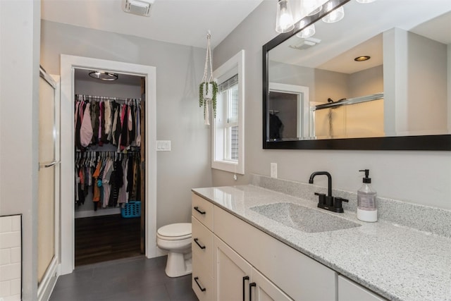 bathroom featuring an enclosed shower, vanity, and toilet