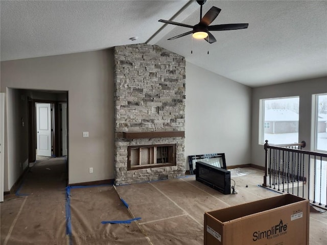 living room with a fireplace, a textured ceiling, ceiling fan, and lofted ceiling