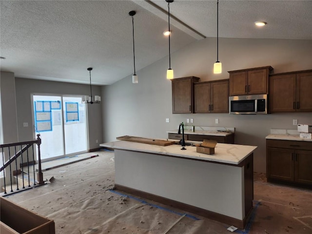 kitchen featuring a chandelier, pendant lighting, a textured ceiling, and a kitchen island with sink