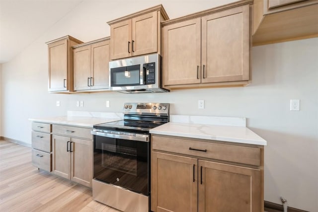 kitchen with light wood-type flooring, light brown cabinets, baseboards, and stainless steel appliances