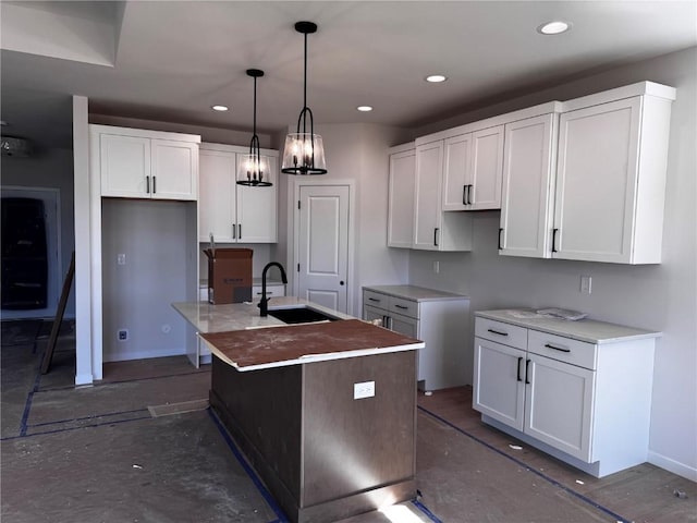 kitchen with pendant lighting, a center island with sink, a sink, white cabinetry, and recessed lighting