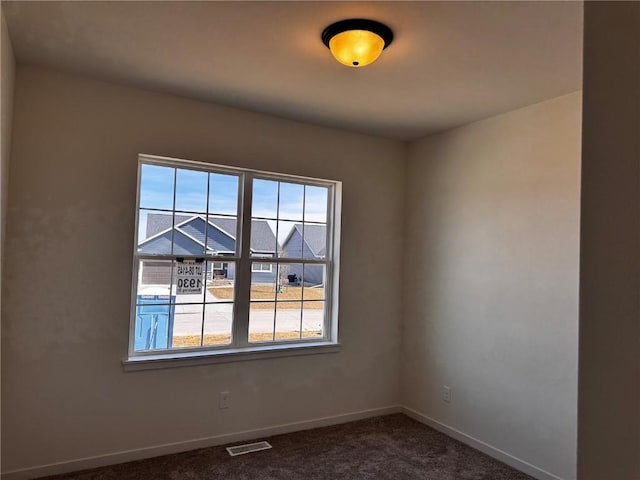 empty room with visible vents, baseboards, and dark colored carpet