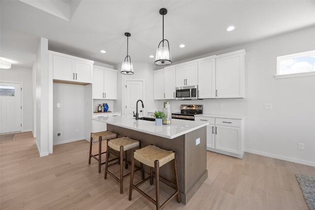 1930 Bowstring Dr, Marion, IA 52302 - kitchen featuring appliances with stainless steel finishes, white cabinets, light wood finished floors, a kitchen breakfast bar, and recessed lighting