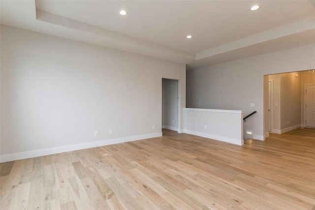 spare room featuring light wood-type flooring and a tray ceiling