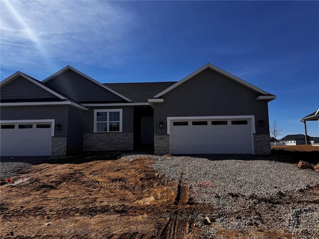 view of front of property featuring driveway, a garage, and stone siding