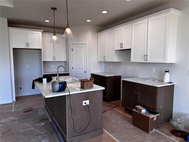 kitchen featuring a sink, white cabinets, recessed lighting, and a center island with sink