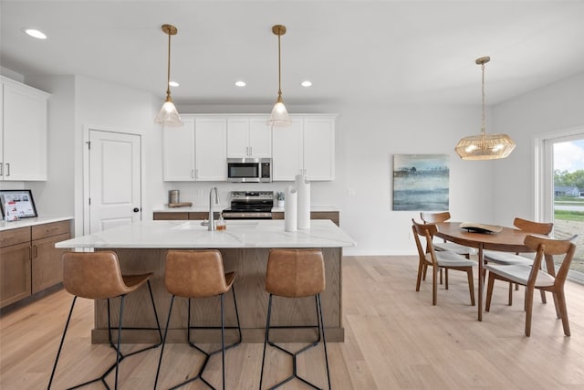 1932 Bowstring Dr, Marion, IA 52302 - kitchen with stainless steel appliances, light wood finished floors, white cabinetry, an island with sink, and recessed lighting