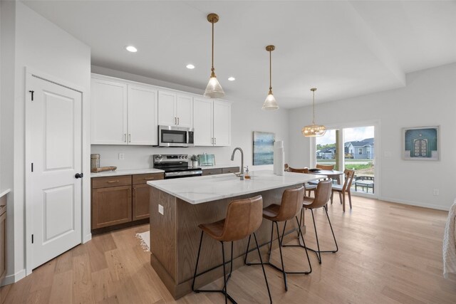 1932 Bowstring Dr, Marion, IA 52302 - kitchen with appliances with stainless steel finishes, light wood finished floors, a breakfast bar, recessed lighting, and a kitchen island with sink