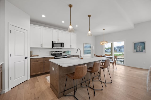 1932 Bowstring Dr, Marion, IA 52302 - kitchen with appliances with stainless steel finishes, light wood-style floors, a breakfast bar, recessed lighting, and a center island with sink