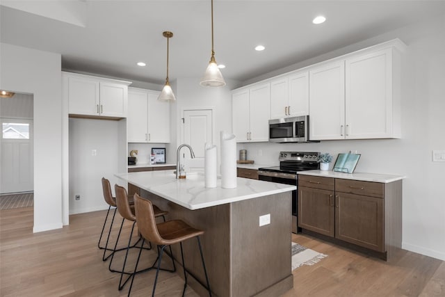1932 Bowstring Dr, Marion, IA 52302 - kitchen with appliances with stainless steel finishes, baseboards, white cabinetry, light wood-style floors, and a breakfast bar